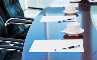 Meeting room table with black chairs, paper and pen and coffee cup